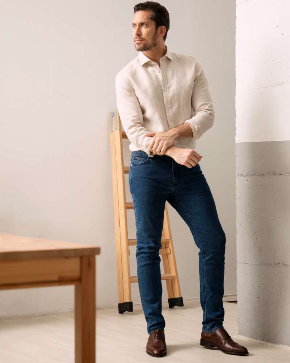 Man posing in tapered jeans and white blouse