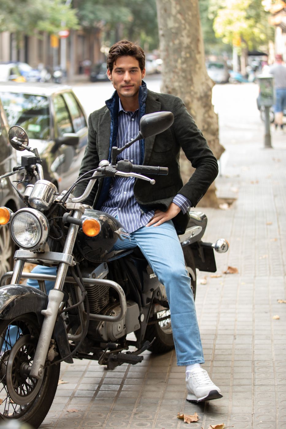 Handsome young man posing in tapered jeans with motorbike
